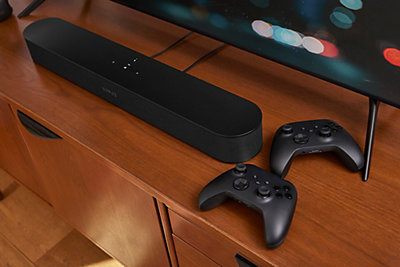 Sonos Beam on entertainment center next to gaming controllers