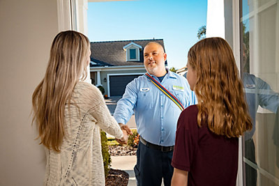 Technician greeting mother and daughter at front door of home