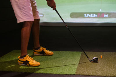 man setting up golf ball in garage with golf simulator