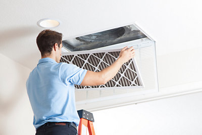 HVAC technician replacing an air filter in home