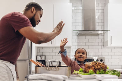 father and daughter celebrating together while cooking thanksgiving dinner