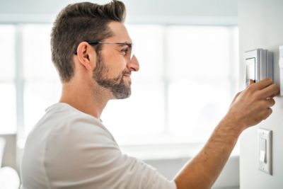 Cheerful man set the thermostat at house