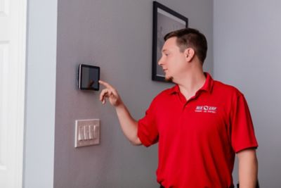 Red Cap technician testing new HVAC unit by adjusting thermostat