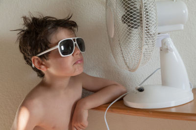 Kid with sunglasses cooling down with fan