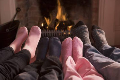 Family snuggling with feet in socks in front of fireplace