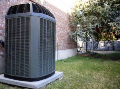 Air conditioning unit outside in front of brick wall