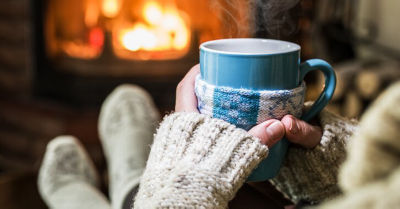 Woman covered with sweater holding the cup