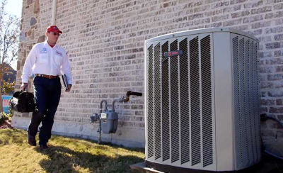 Technician walking up to AC unit with toolbag