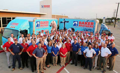 Baker Brothers employees in front of trucks with headquarters in background