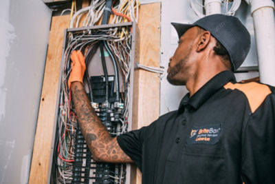 Electrician is inspecting and interacting with wires set in a wall. 