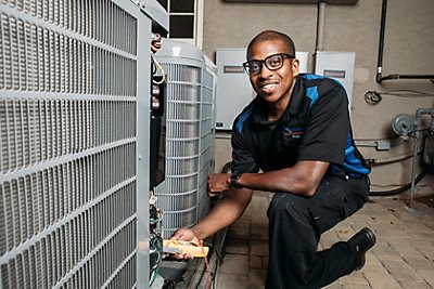Coolray technician smiling in front of HVAC system