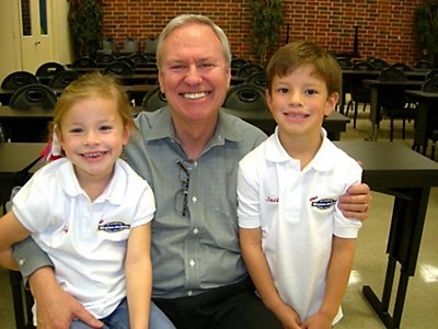 Mr. Jenkins smiling with happy grandchildren  sitting on his kneews