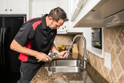 Plumber inspecting water flowing from faucet