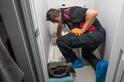 Plumber repairing a toilet in a Smyrna, GA home