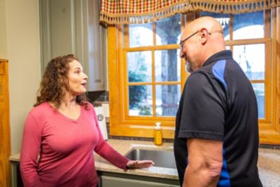 HVAC tech talking with homeowner in kitchen