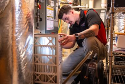 HVAC technician inspecting furnace with flashlight
