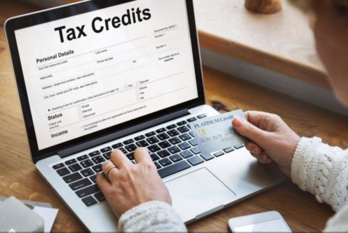 Opened laptop on a wood desk showing a white Tax Credits screen.