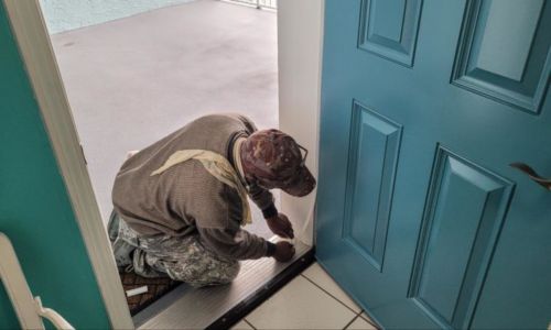 Man applying weather stripping to an exterior door frame