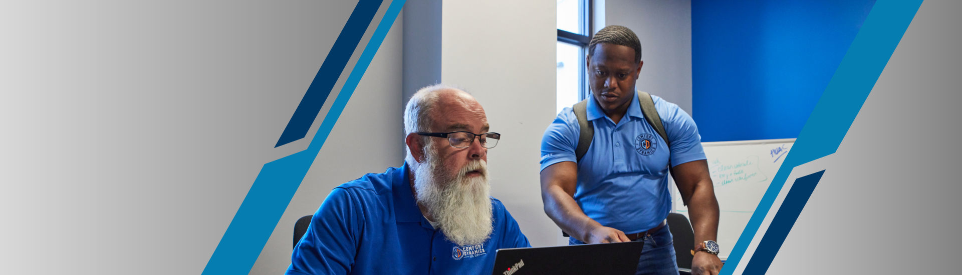 a person in a blue shirt and glasses looking at a laptop