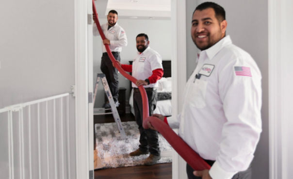 Three techs smiling and cleaning out a dirty air duct