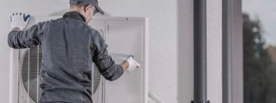 a person wearing a cap and gloves working on a white machine