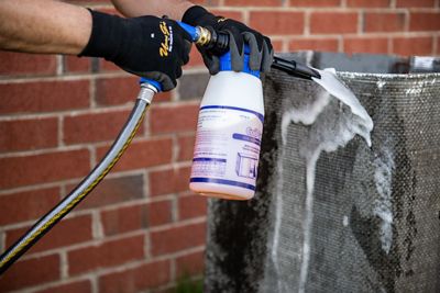 A dirty air conditioner in front of a brick wall.