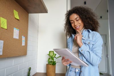 Smiling african teen girl, afro american college student, ethnic school pupil, remote worker studying, distance learning holding notebook in hands, thinking, making notes working from home office.