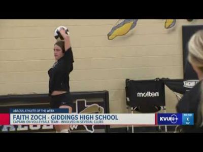 A woman holding a volleyball over her head.