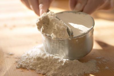 A person pouring flour into a measuring cup
