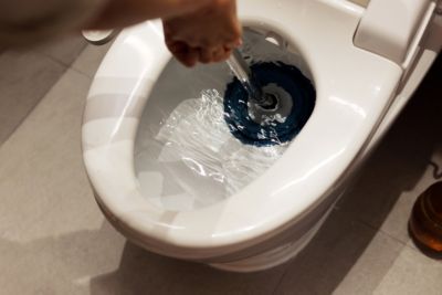 hand holding a plunger unclogging a home toilet