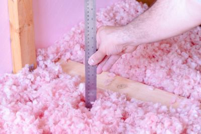 Clean work, checking the energy efficiency of their house by measuring the thickness of fiberglass insulation in the attic