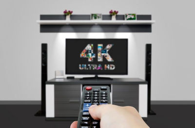 Hand pointing remote at 4k Ultra HD flat screen