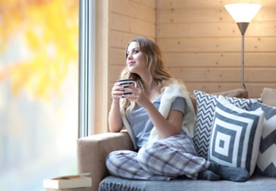 A woman sitting on a couch and looking out a window.