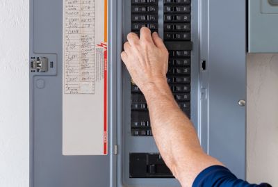 An electrician reaching into an electrical panel