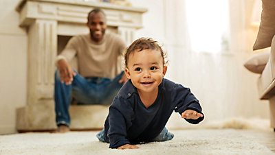 Cute baby crawling away from man in living area
