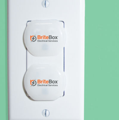 Outlet with BriteBox safety covers on green wall