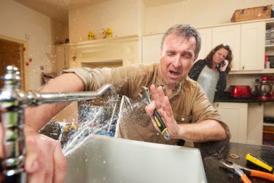 Kitchen sink spraying man in the face as a women talks on the phone