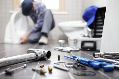 Floor view of plumber fixing toilet and tools