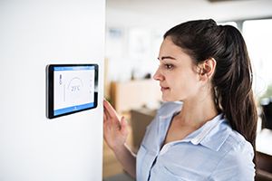 Woman adjusting thermostat in her home