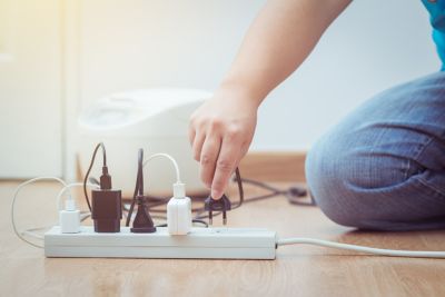 Small child's hand plugging plug into surge protector