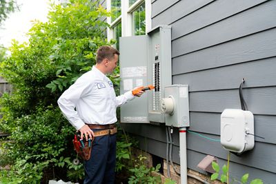 technician testing circuit breaker on outdoor electrical panel