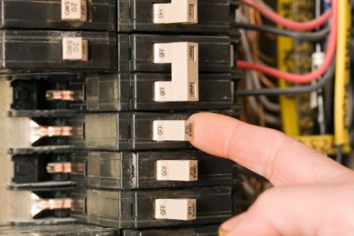 Finger touching a circuit breaker apart of an electrical panel