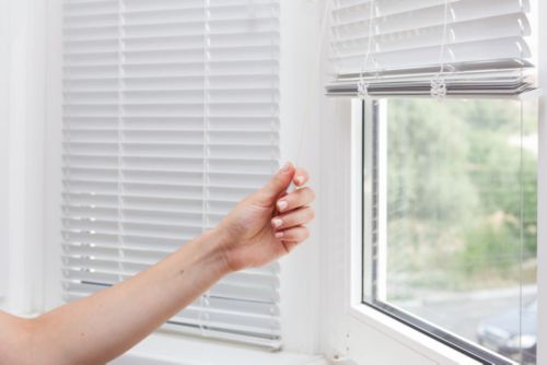 A hand holding a string near a window