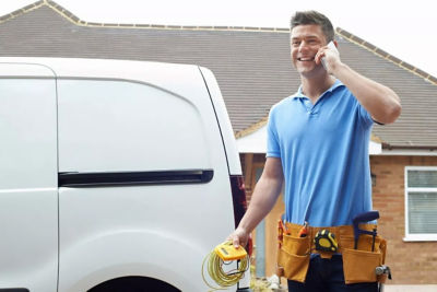 Image of a man in a toolbelt smiling and talking on the phone