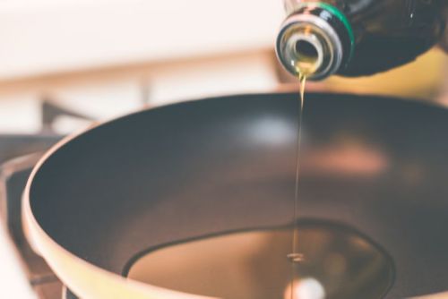 A close-up of a bottle pouring oil into a bowl