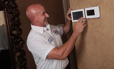 Technician smiling while looking at digital thermostat