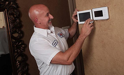 Technician smiling while inspecting digital thermostat