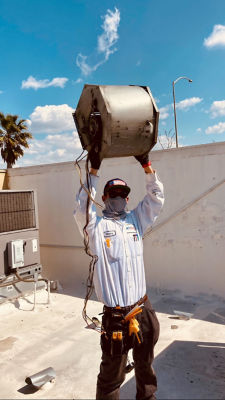 A man holding an AC part over his head.