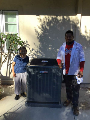 A man and a woman standing next to a NexGen AC unit.