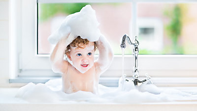 Cute baby in kitchen sink with bubbles